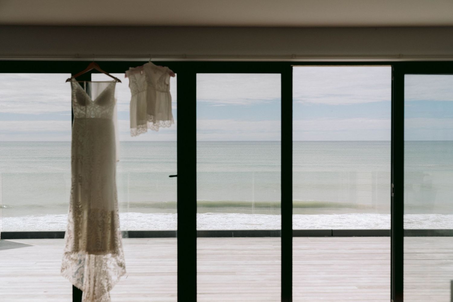 Large windows with black frames overlooking a tranquil ocean view and white sandy beach.