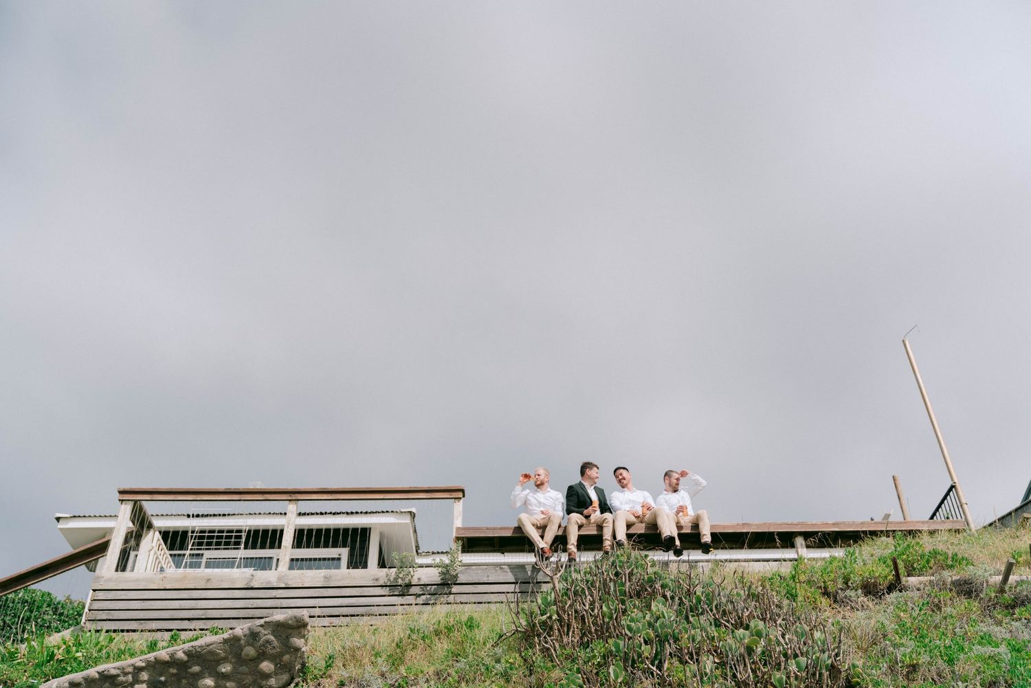 Small group sits atop a hillside structure against a cloudy gray sky.