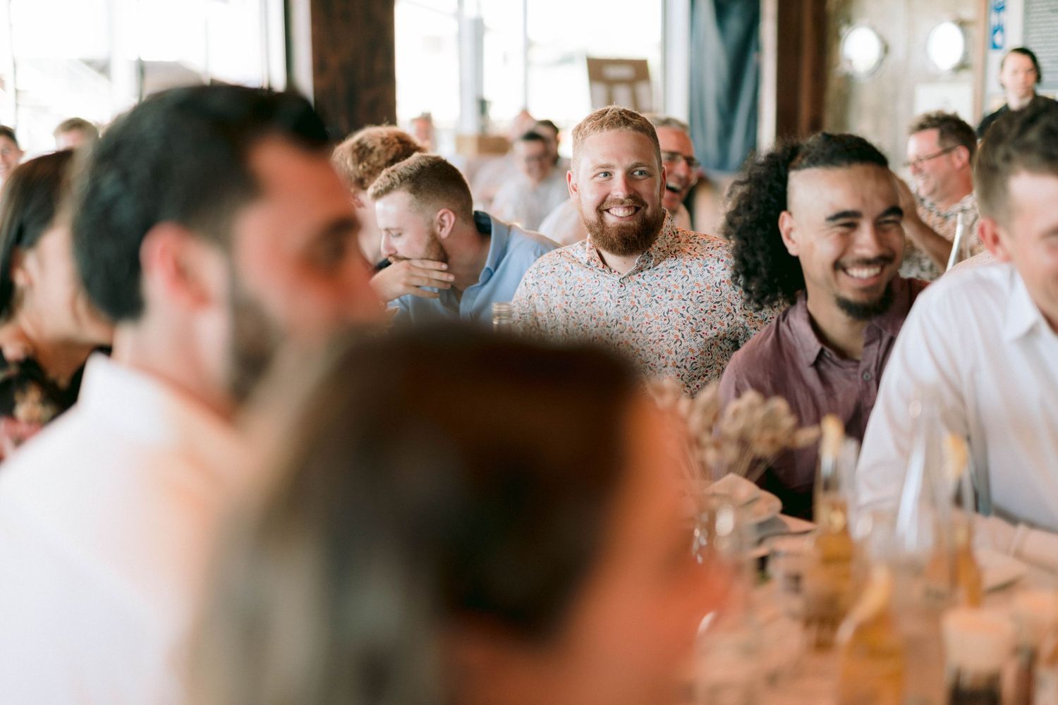 Wedding guests laugh and smile during a reception celebration.