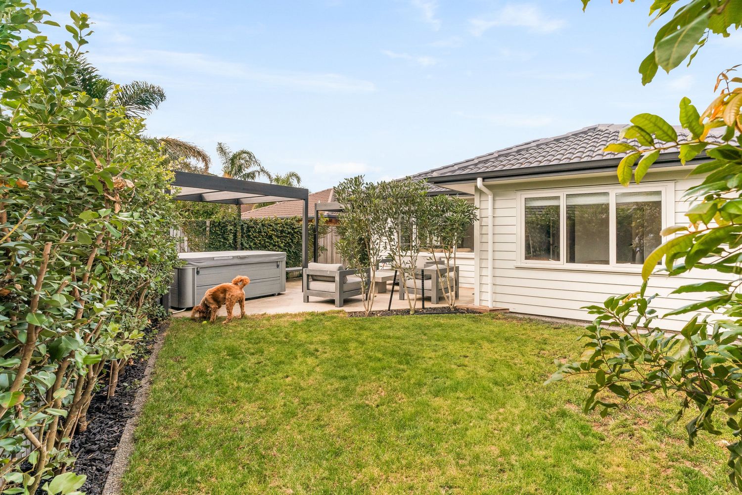 Spacious backyard with lush grass, surrounding trees, and patio area perfect for outdoor living.
