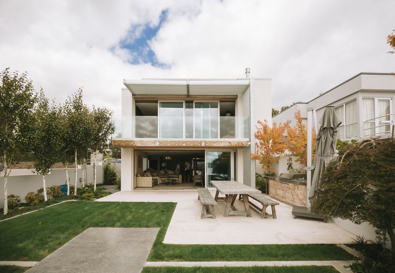 A modern white minimalist house with floor-to-ceiling windows and a seamless indoor-outdoor living space design.