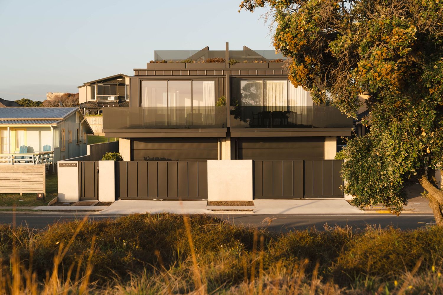 Contemporary architectural homes with dark exterior features nestled among autumn trees.