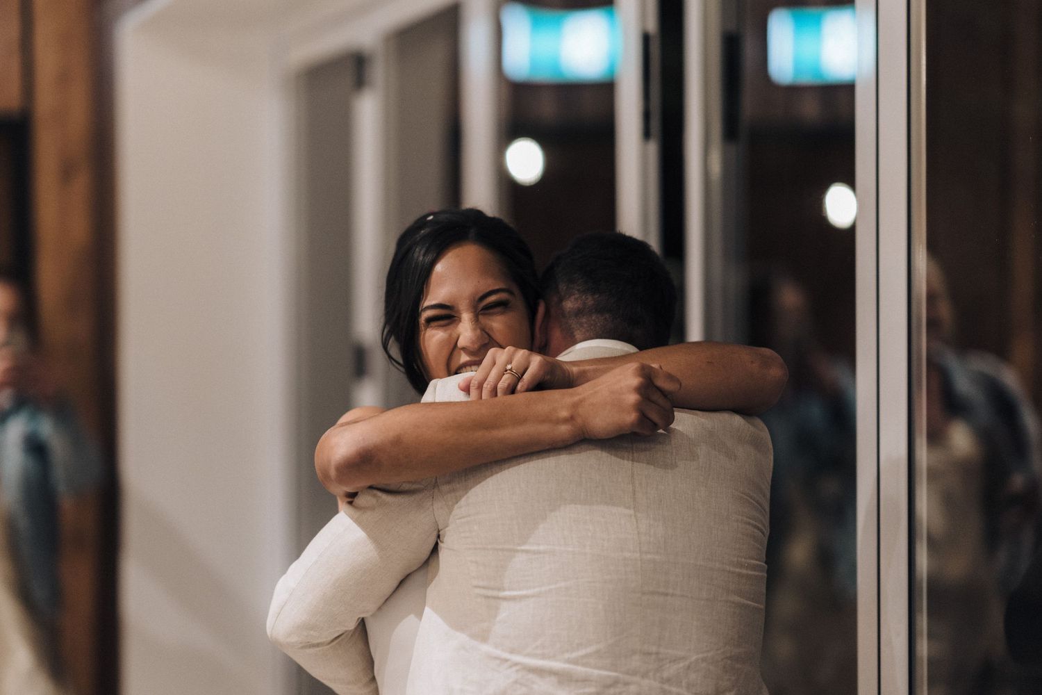 An intimate moment captured during a wedding reception with soft indoor lighting.