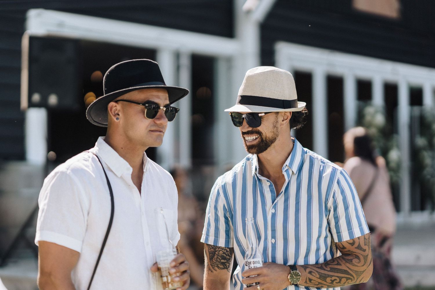 Two friends in summer attire sharing drinks and conversation outdoors.