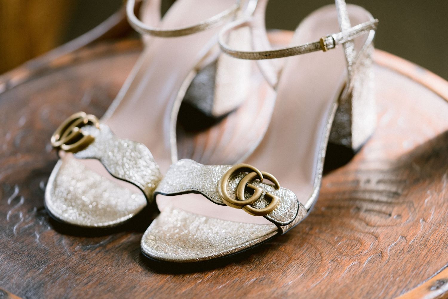 Sparkly white bridal shoes and accessories arranged on a rustic wooden surface for wedding day preparation.