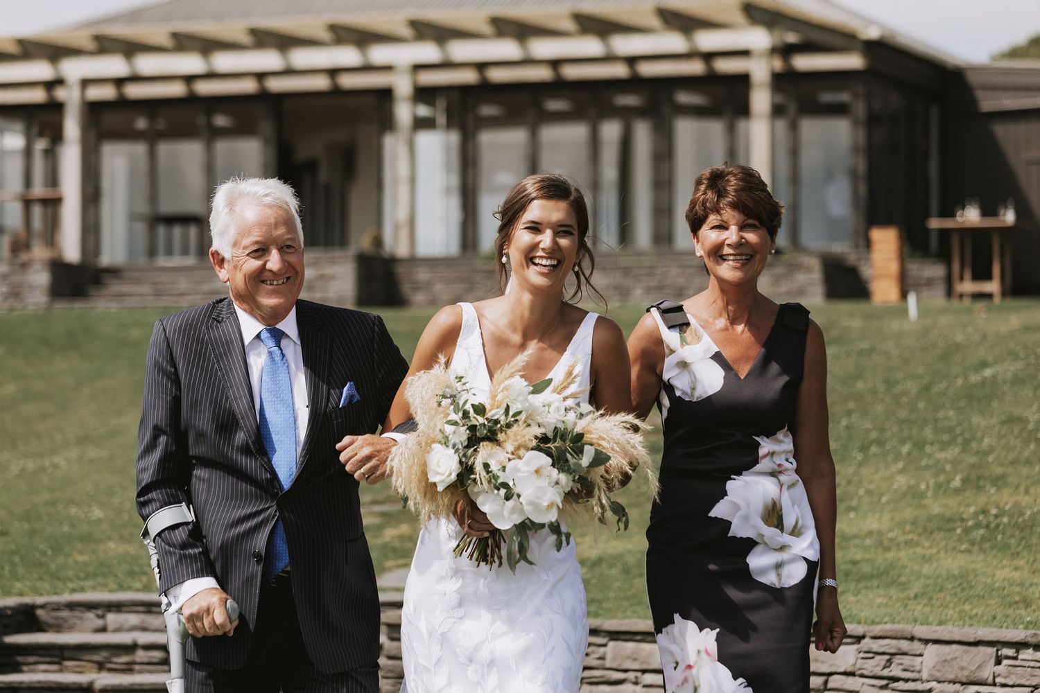 Wedding party celebrates outdoors during a sunny ceremony with natural scenery and joyful reactions.