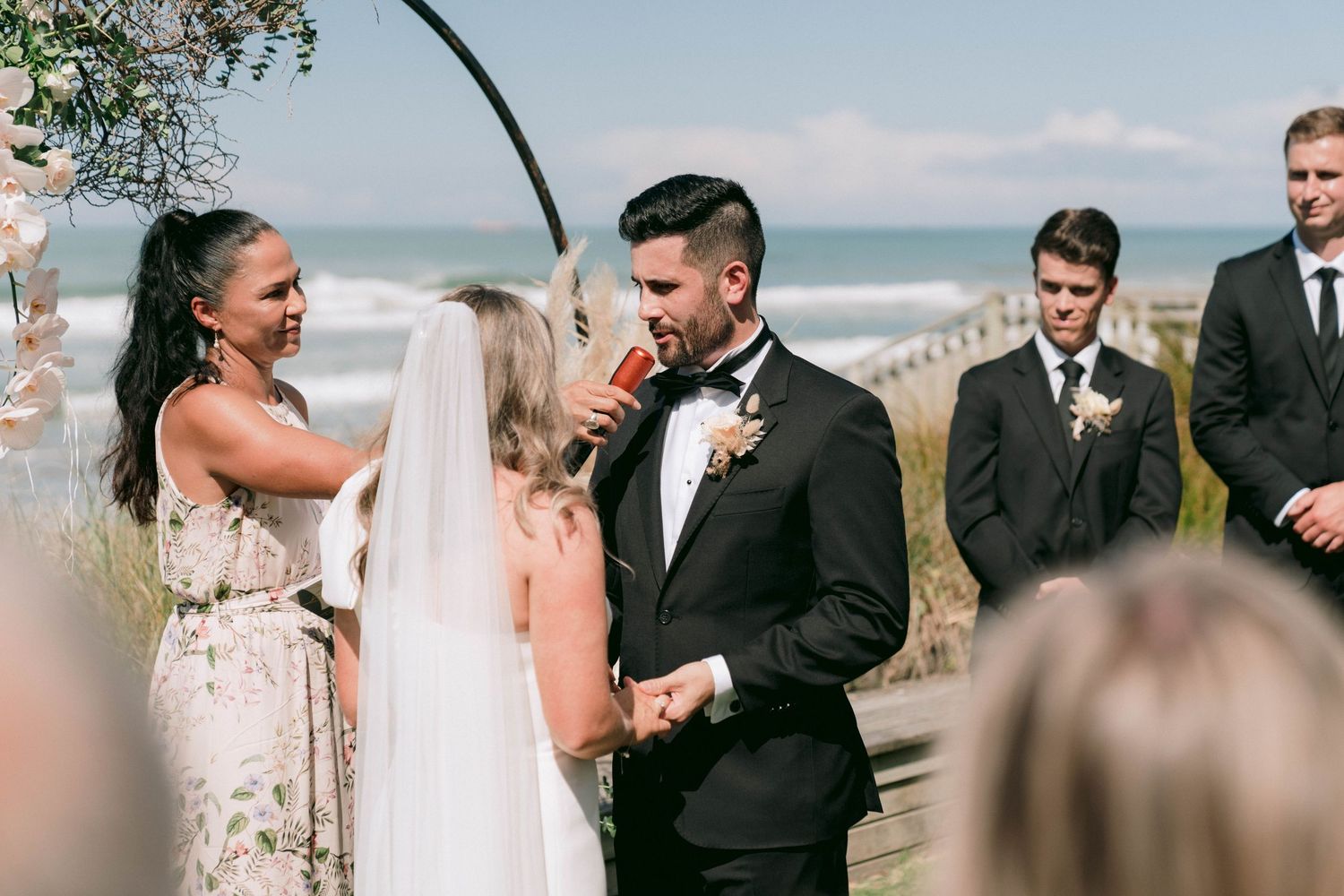 A beachside wedding ceremony with guests enjoying an intimate outdoor celebration by the ocean.