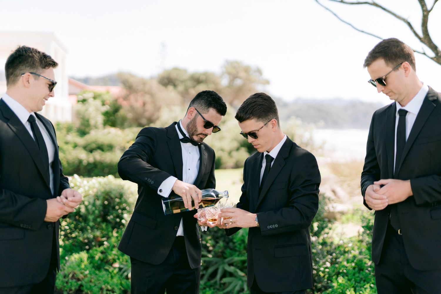 A series of five photos showing a black-suited group standing together in an outdoor natural setting.