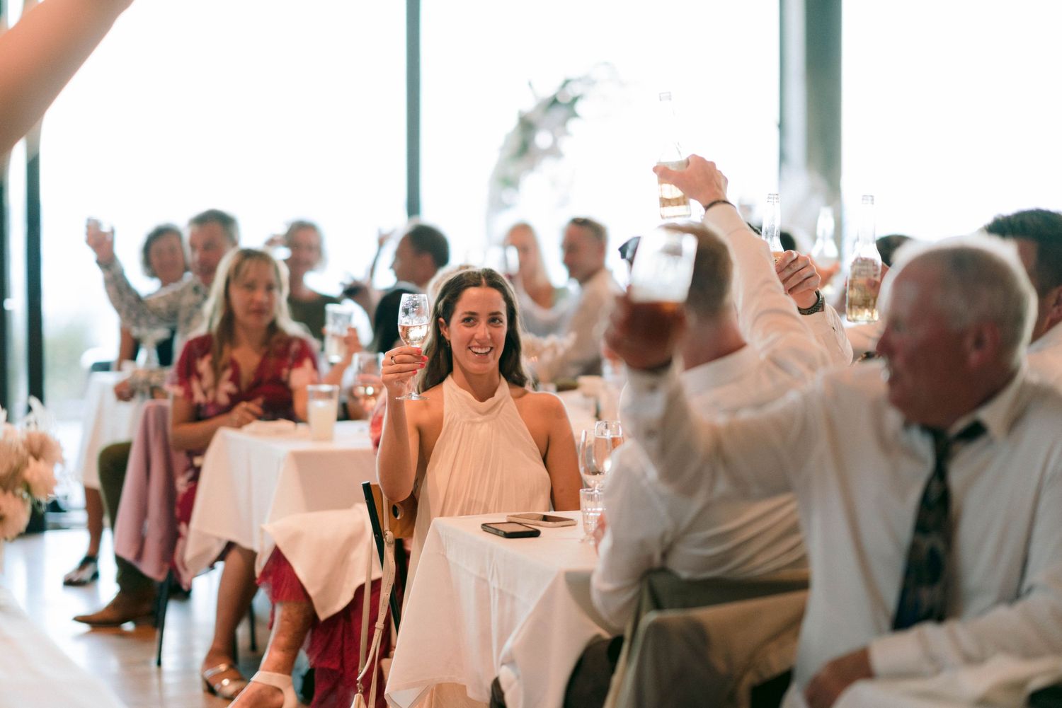 Wedding guests raise their hands in celebration during reception dinner.