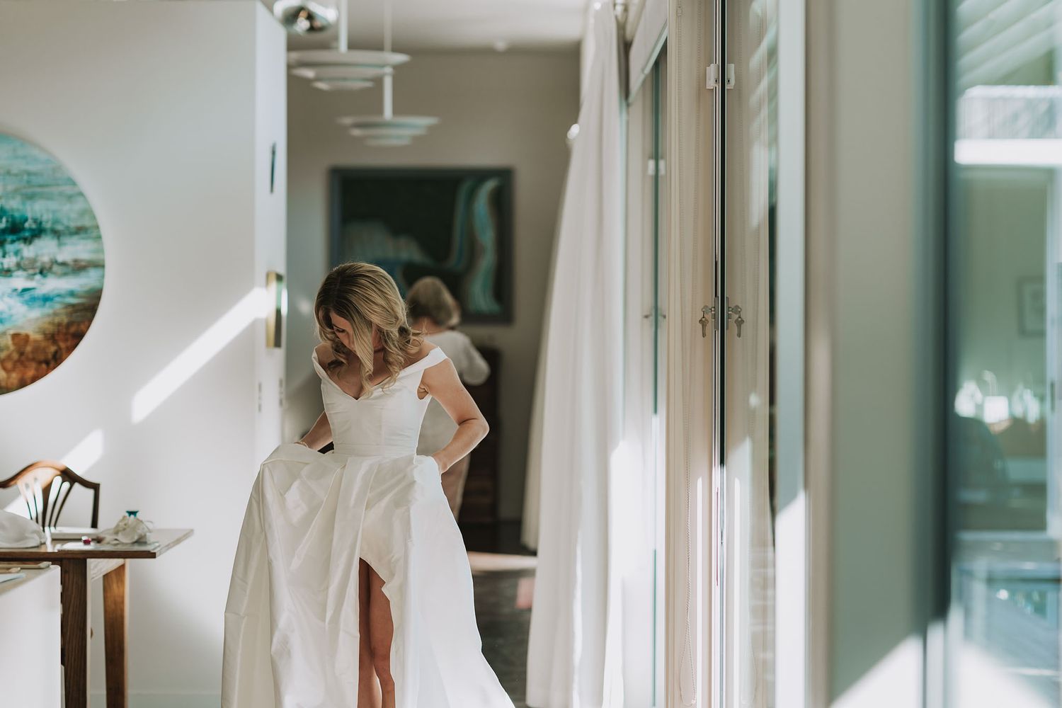 A sunlit hallway interior with a flowing white wedding dress visible in soft natural light.