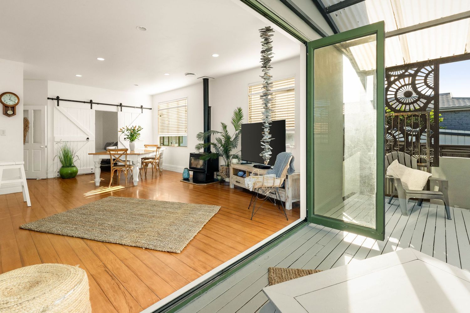 Modern open concept living room with hardwood floors, barn door, and outdoor deck access.