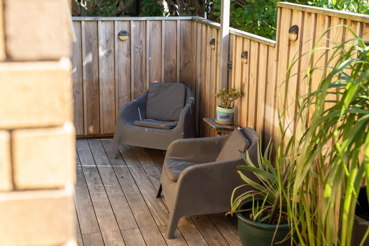 Wooden deck terrace with outdoor seating and potted plants creating a cozy garden atmosphere.