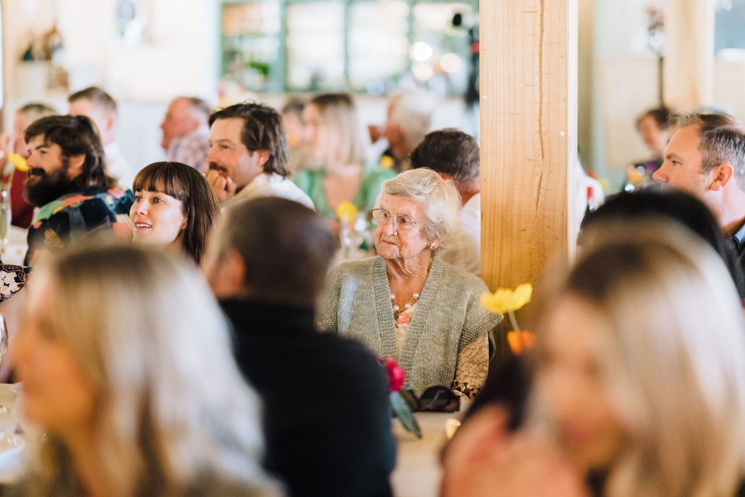 Wedding reception guests enjoying celebration in bright indoor venue.