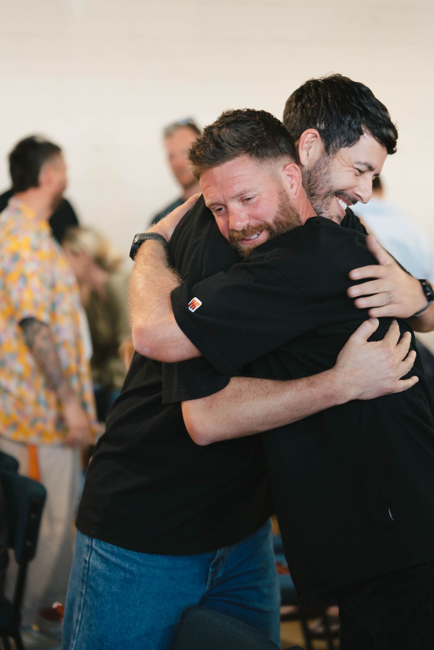 People sharing emotional embraces during a community gathering.