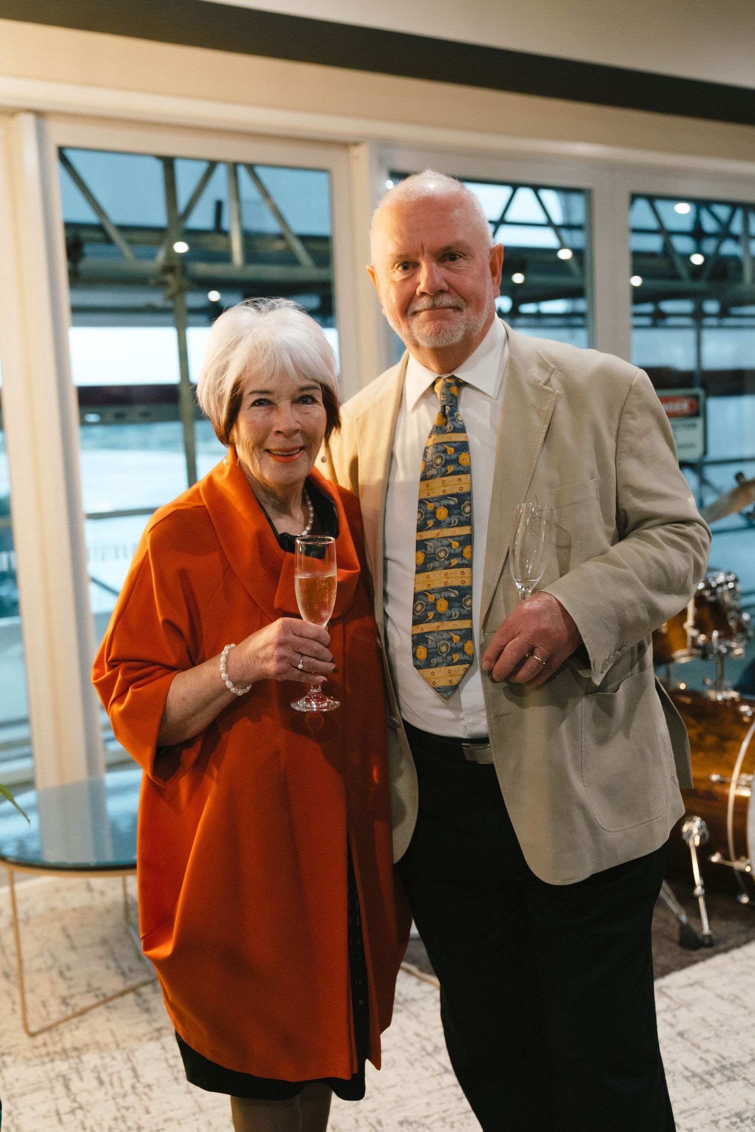 Attendees in formal attire holding champagne glasses at an evening reception.