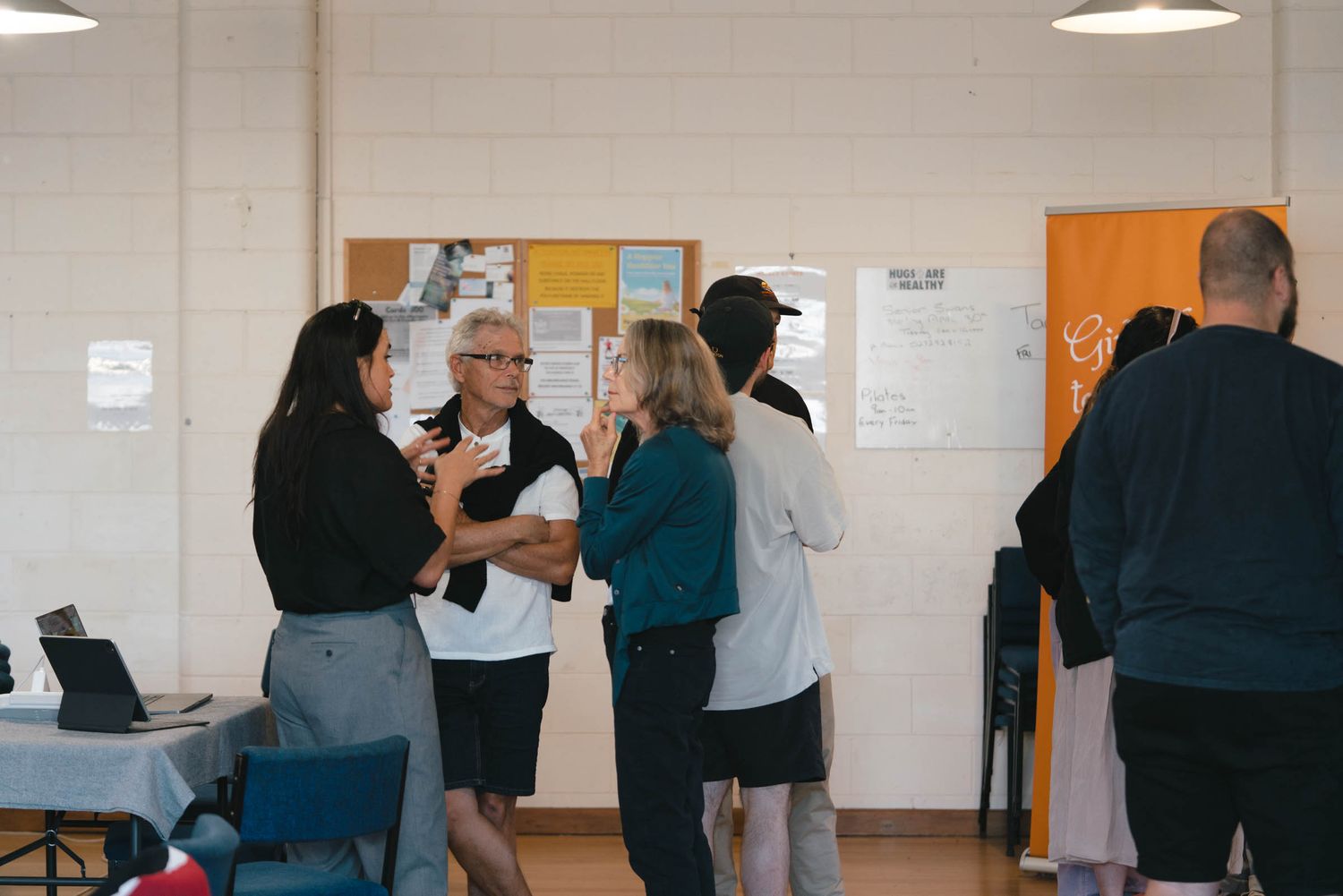 Small groups of people mingling and chatting in a community hall.