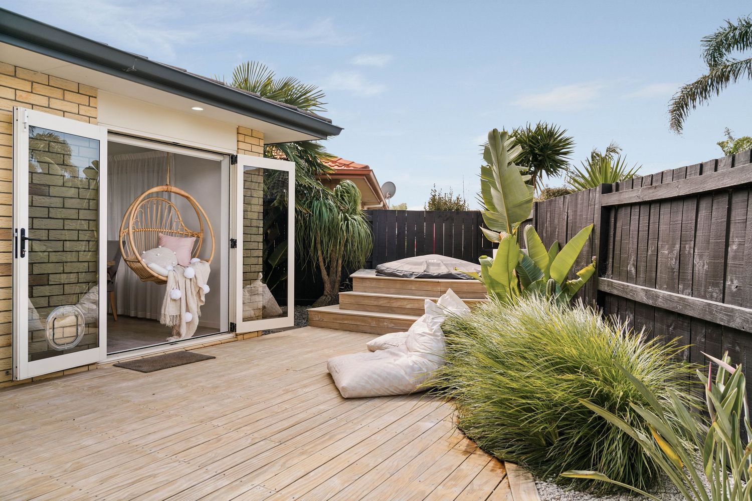 Outdoor deck space with tropical palm trees, wooden fencing, and comfortable seating areas.