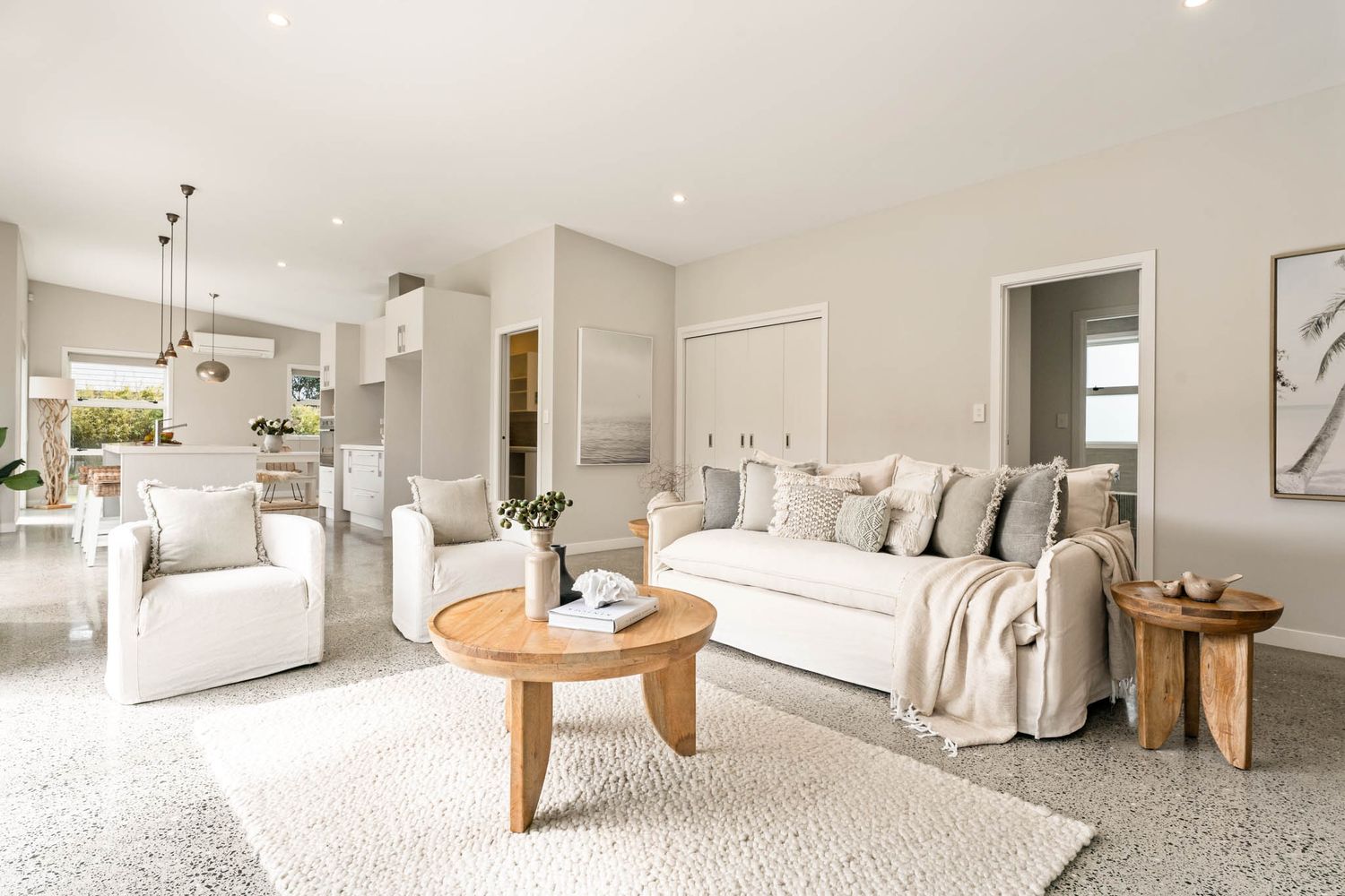 Modern open concept living room with light gray sofa sectional, circular coffee table and neutral coastal decor style.