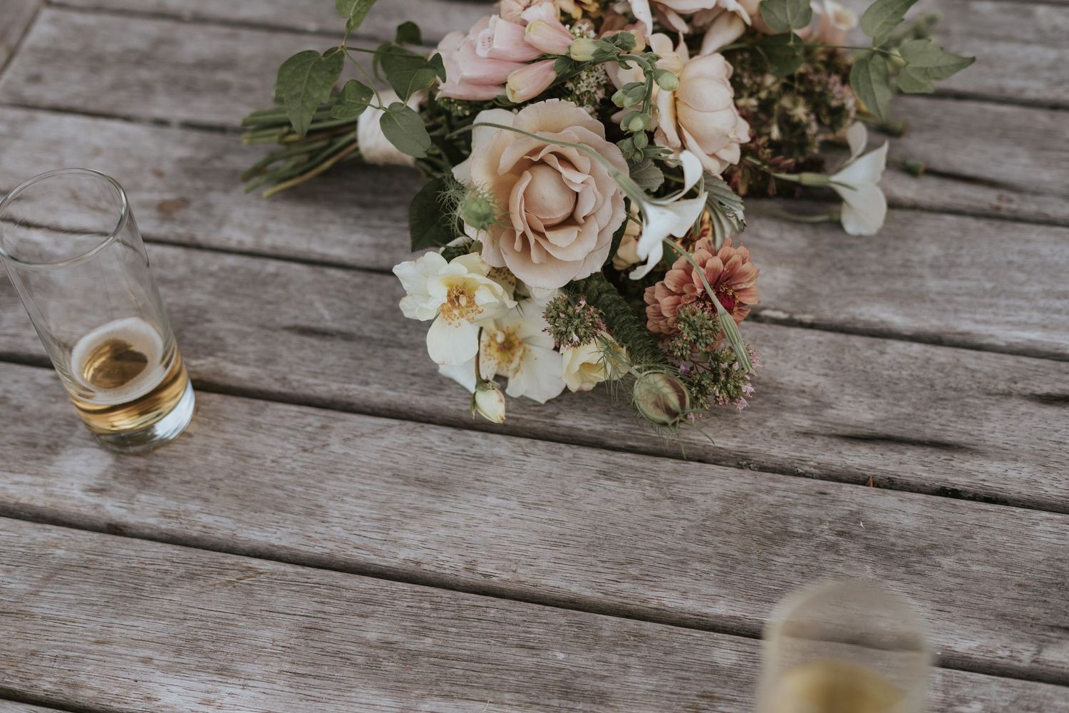 Wedding bouquet with blush pink roses and eucalyptus arranged on rustic wooden planks.