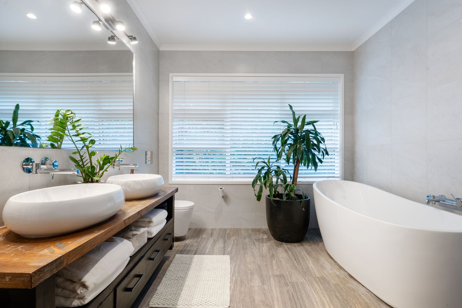 Luxurious bathroom featuring freestanding tub, wood accents and natural light.