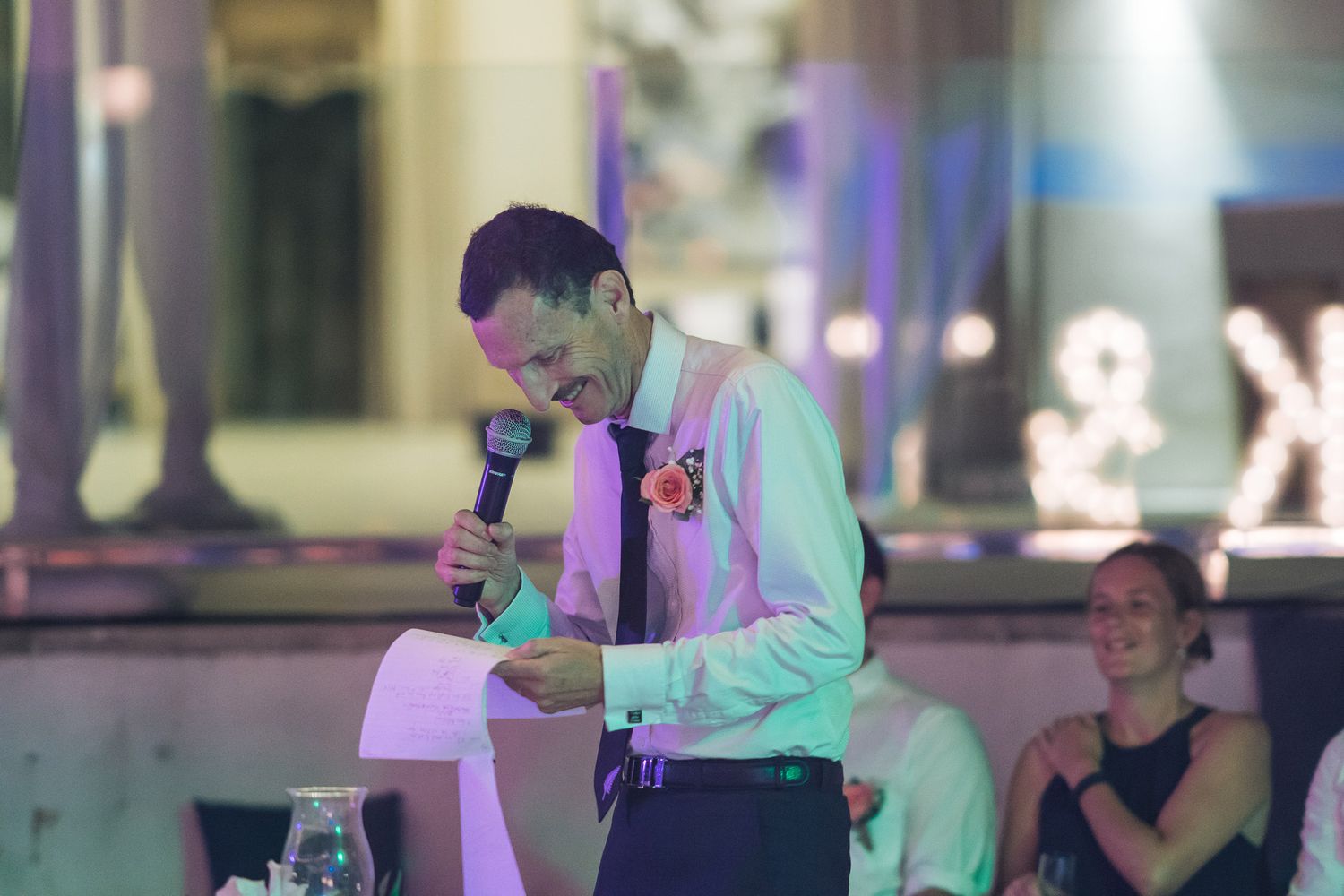 Person giving emotional speech at dimly lit indoor wedding reception.