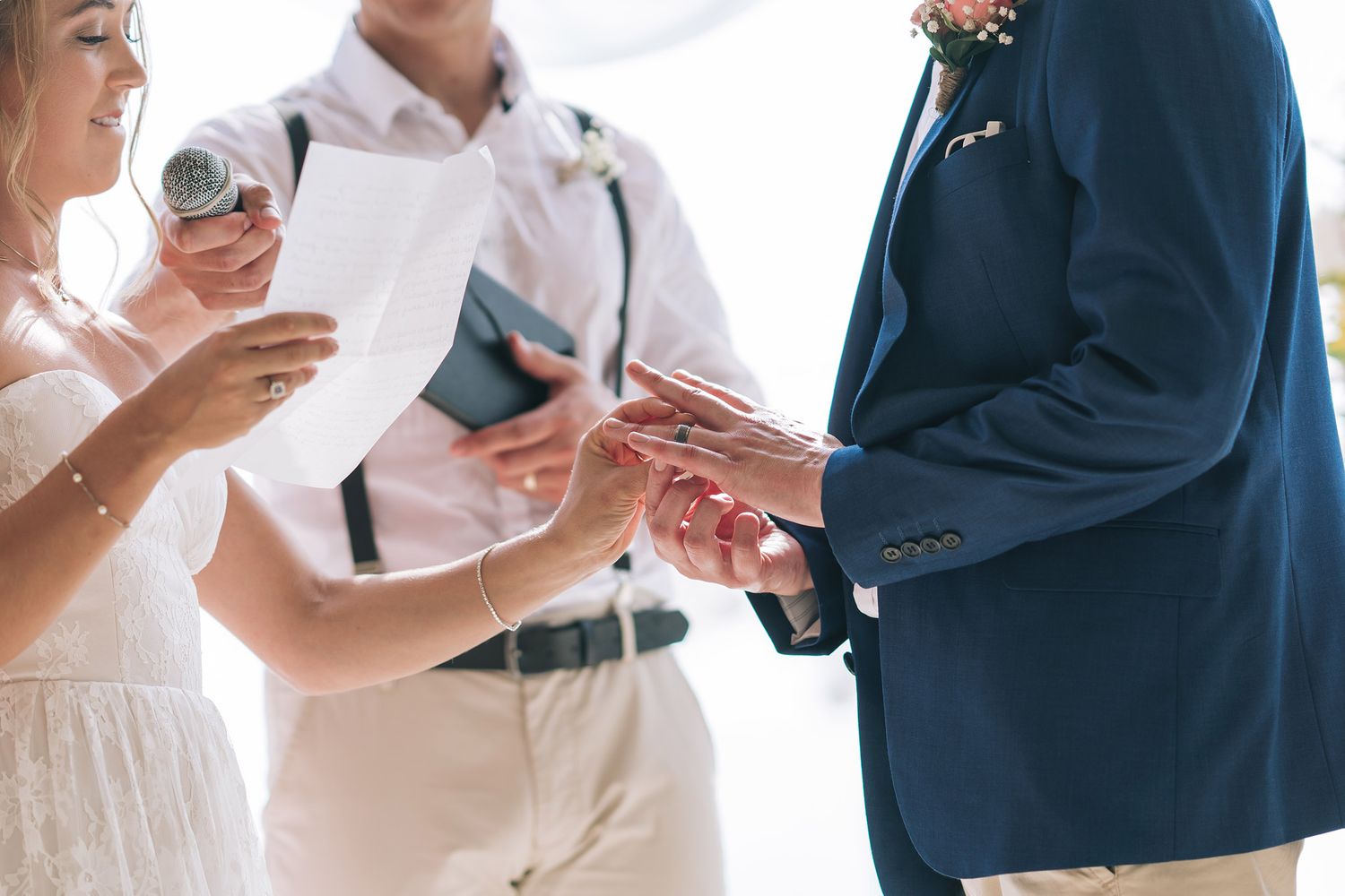 Wedding ceremony attendees exchanging items in formal dress.