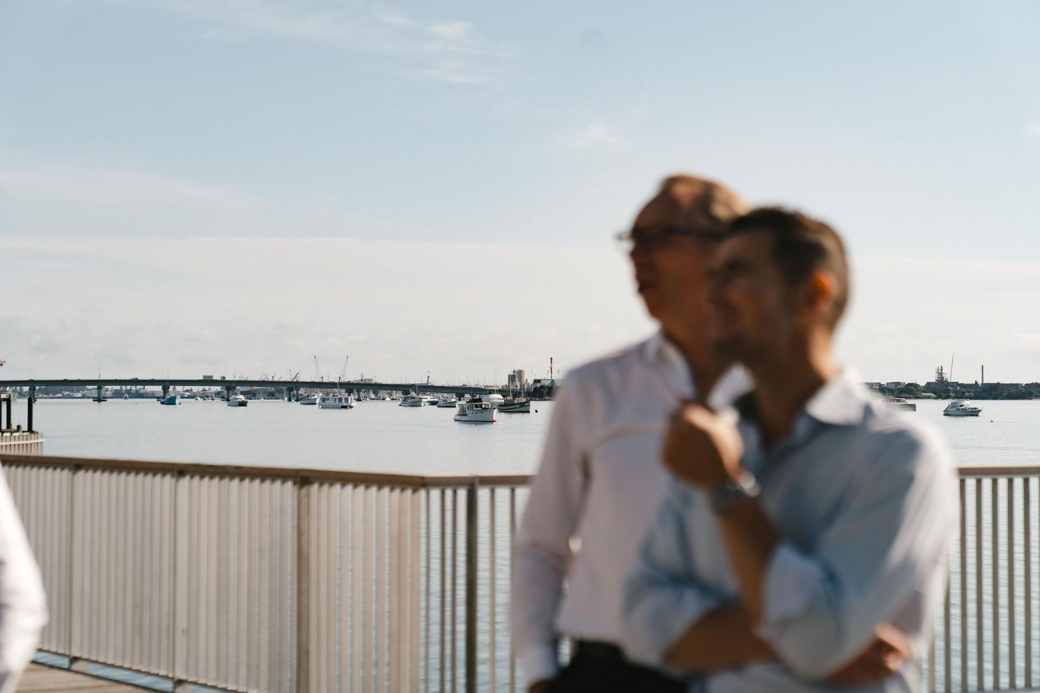 A romantic moment overlooking a marina with boats in the background on a sunny day.