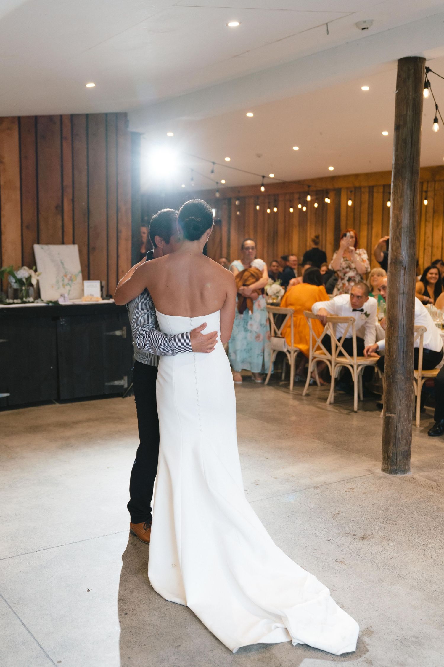 Newlyweds sharing their first dance in a rustic barn reception space.
