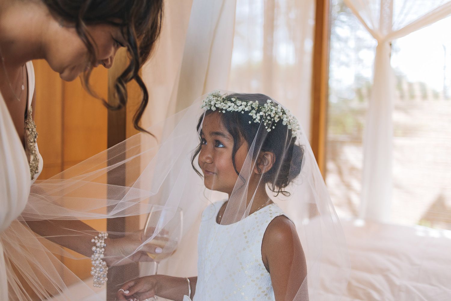 A heartwarming moment between a child wearing a tiara and veil and another person in elegant wedding attire.