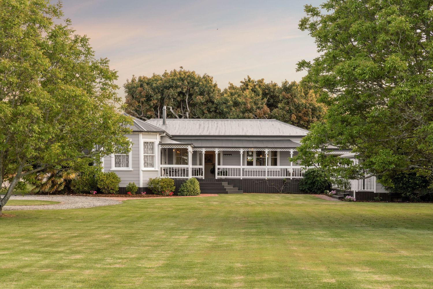 Side view of a contemporary ranch house with wraparound porch and manicured landscaping.