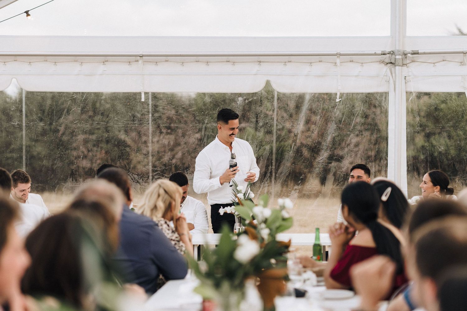 Outdoor wedding reception setup with string lights and natural surroundings.