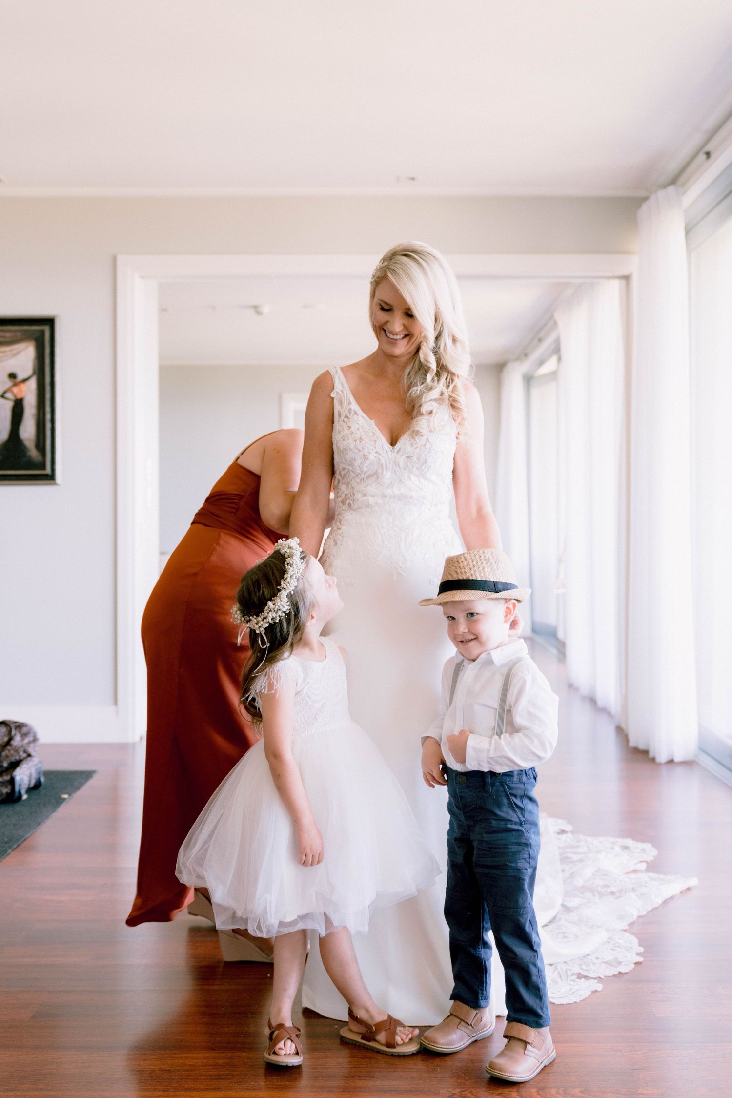 Sweet moment shared between person in white dress and small child standing together in bright indoor hallway space.