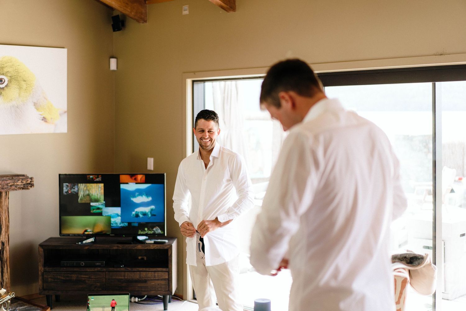 Two people in white dress shirts preparing in a modern room with television.