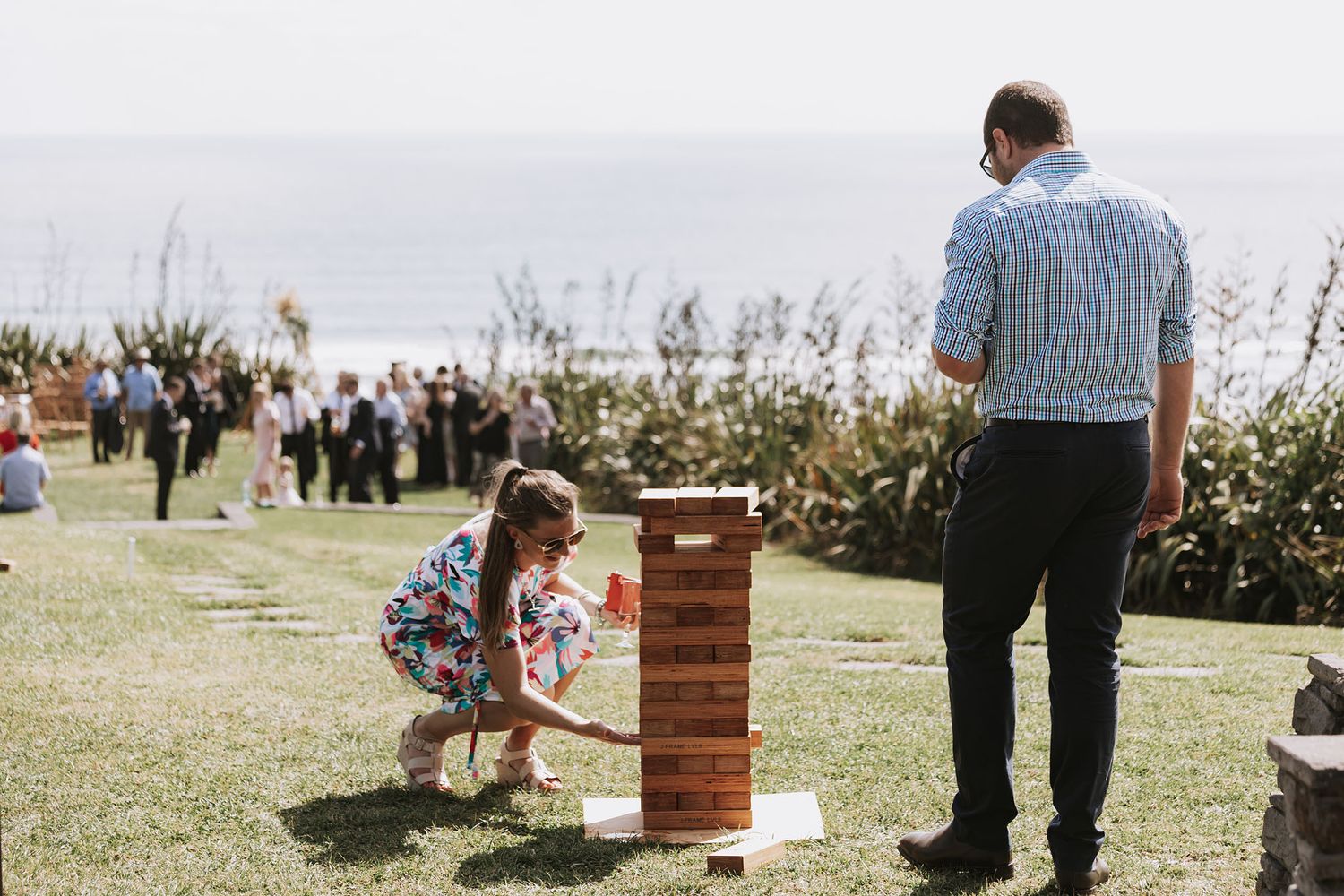 Five connected photos showing guests at an outdoor wedding ceremony in a natural grassy field setting during sunset.
