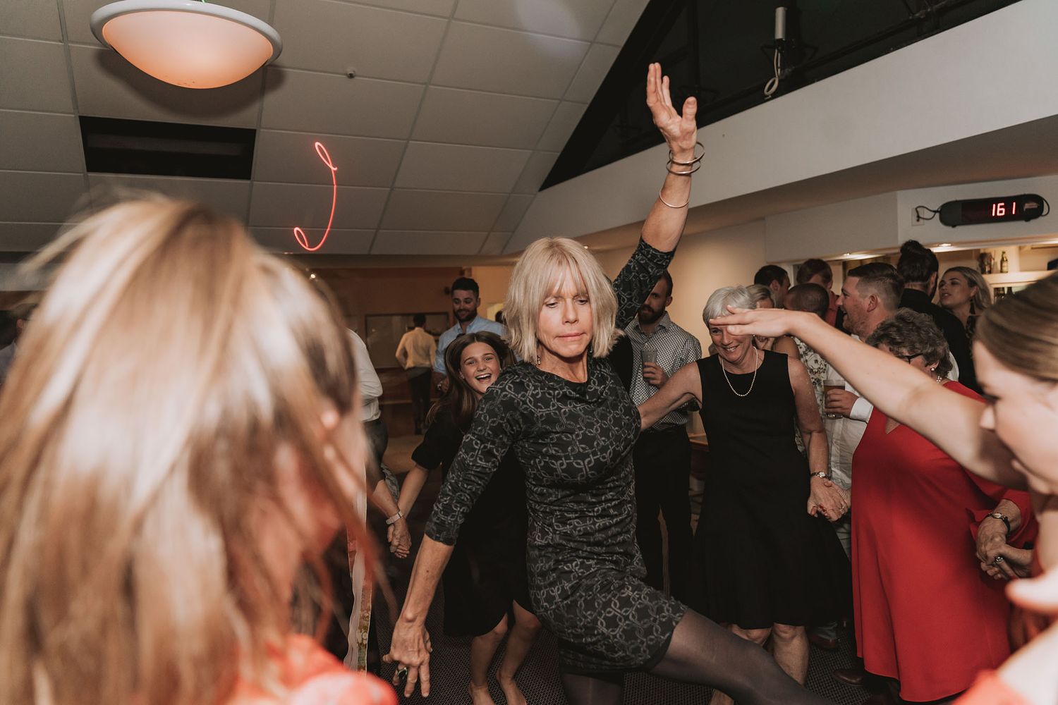 Happy partygoers dancing and celebrating together on a dimly lit dance floor at an evening event.