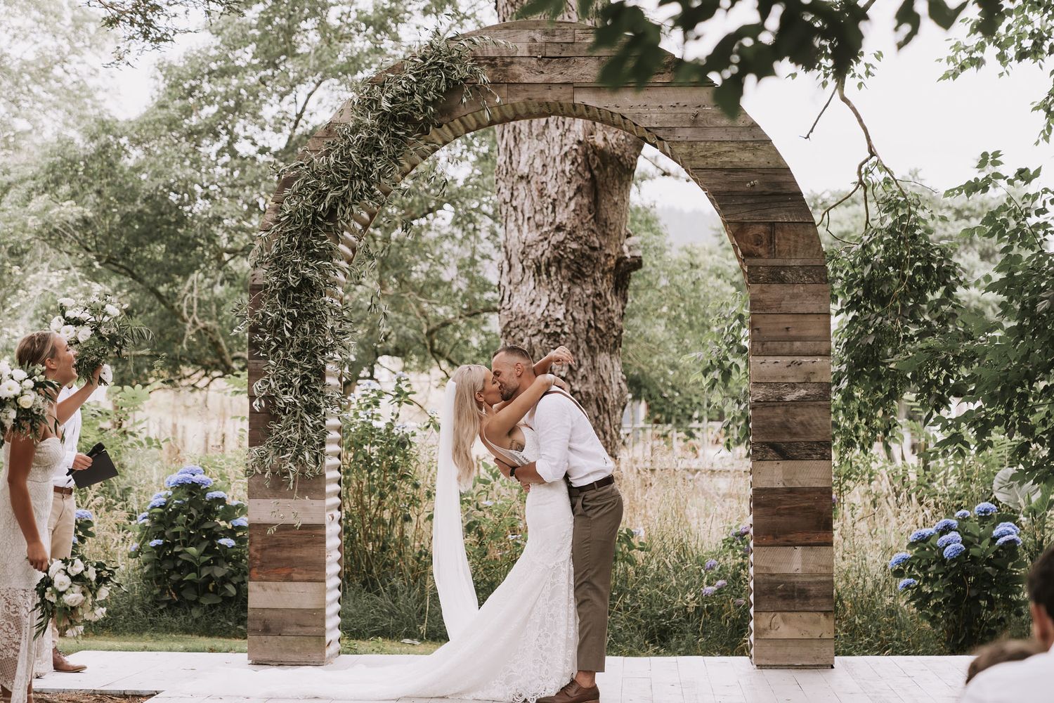 A couple shares romantic moments under multiple rustic stone arches in a garden setting during their wedding photo session.