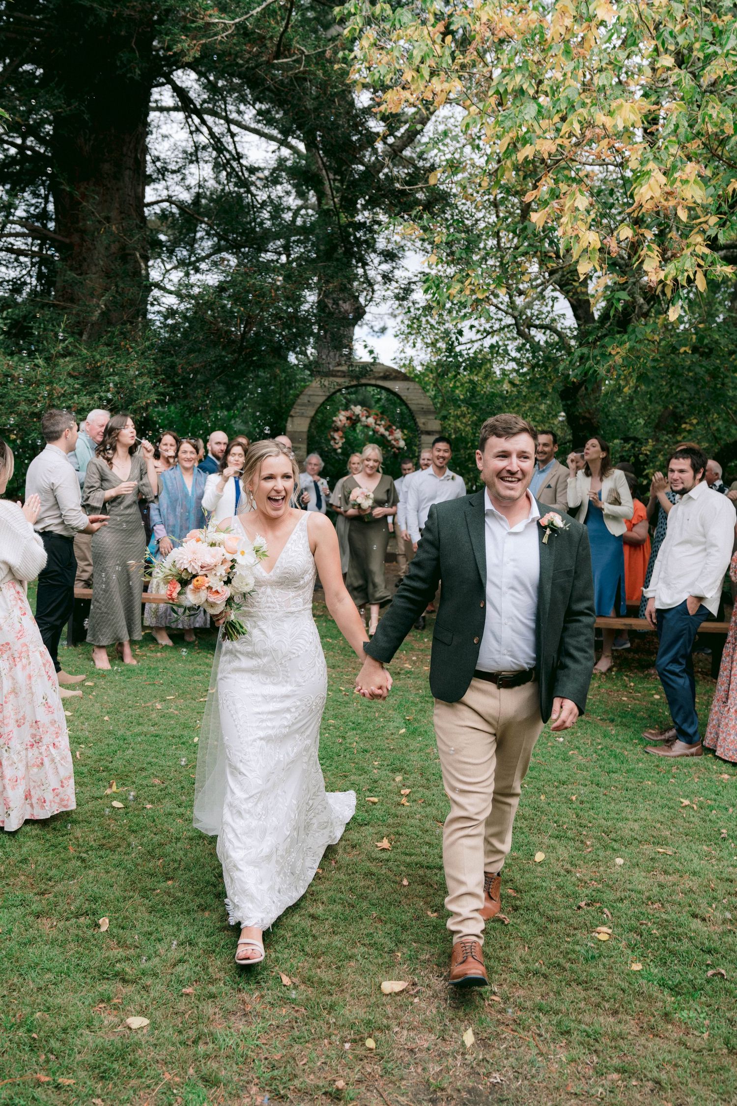 Wedding guests celebrating on grassy lawn during outdoor reception.