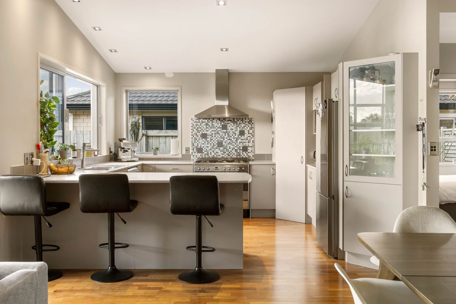 Modern open concept kitchen with white cabinets, quartz countertops, and sleek bar seating along a peninsula.