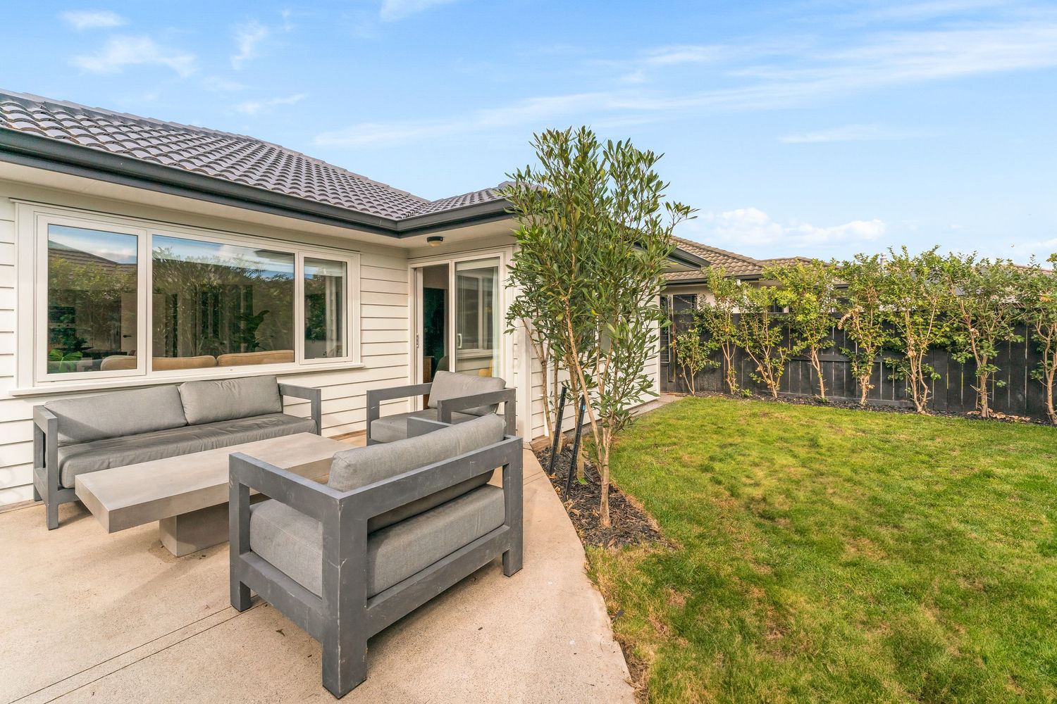 Modern outdoor deck with grey composite seating and railing overlooking a landscaped yard.