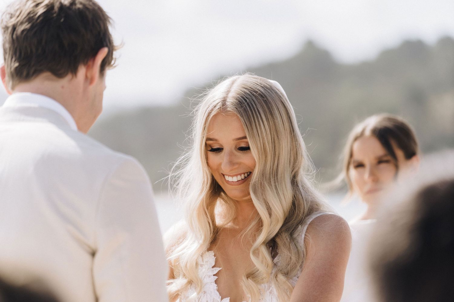 An intimate moment during a sunny outdoor wedding ceremony showing a happy couple exchanging vows.