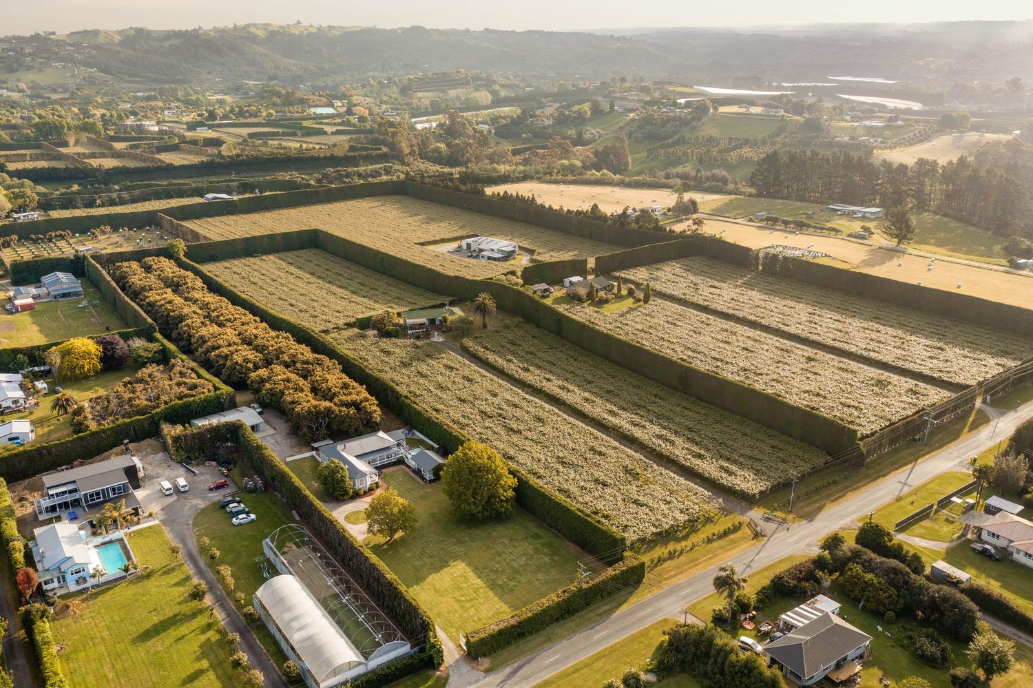 Aerial view of expansive industrial warehouses and storage facilities with rolling hills in the background during sunset.