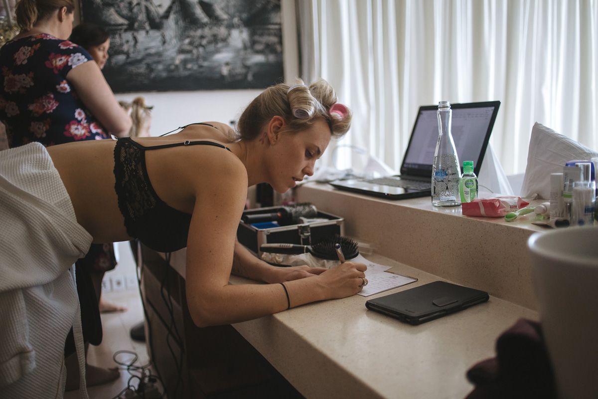 Person focused on writing or studying at a desk with a laptop and water bottle nearby.