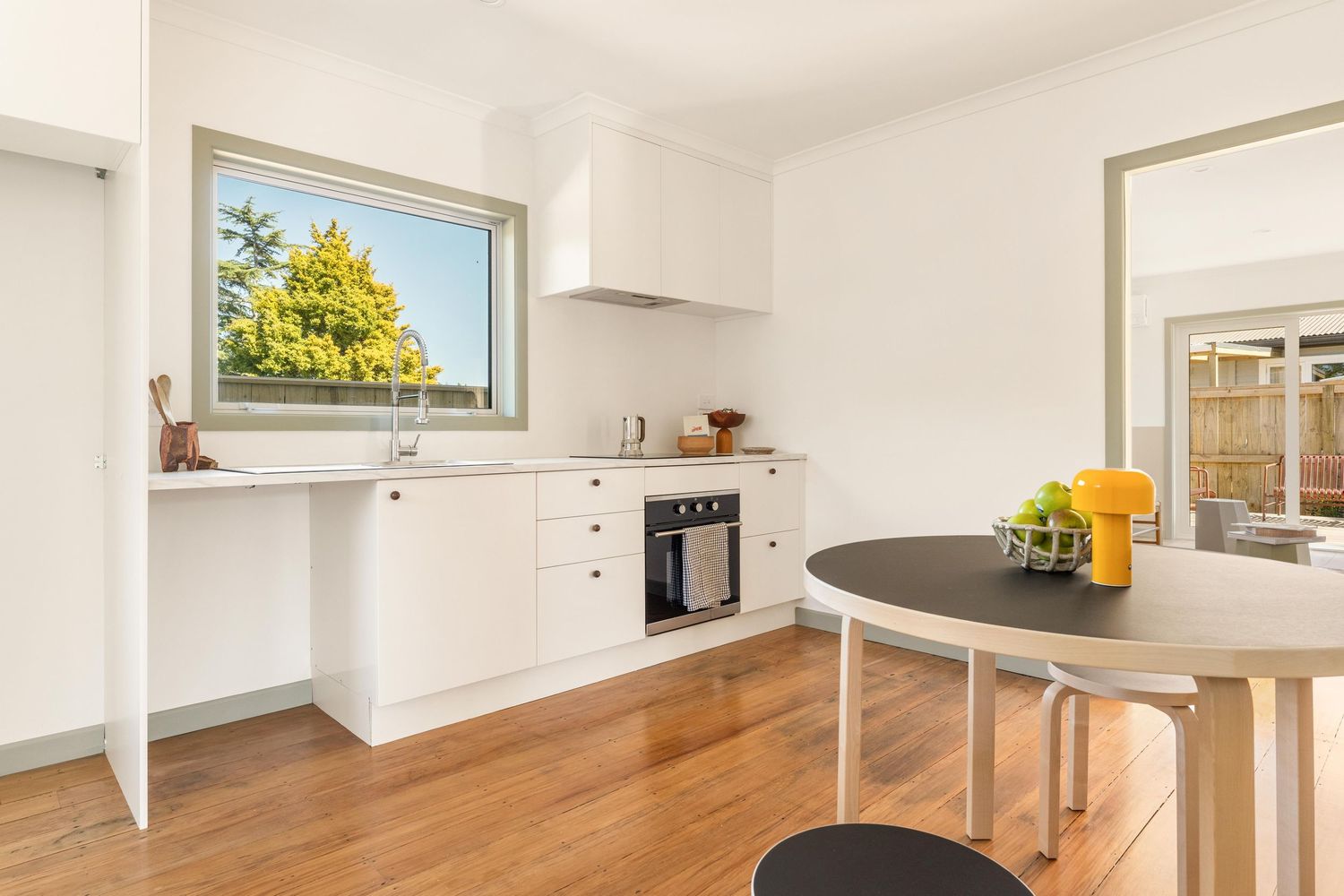 Contemporary kitchen with round dining table and black chairs facing white cabinetry.