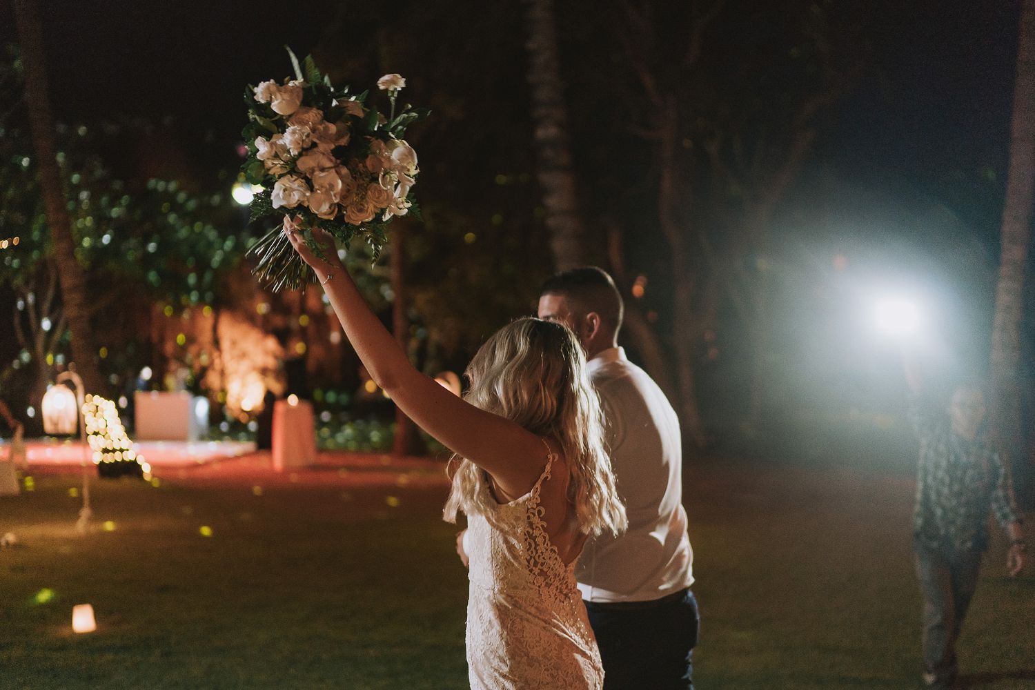 Couples dancing under romantic evening lighting at an outdoor wedding reception.