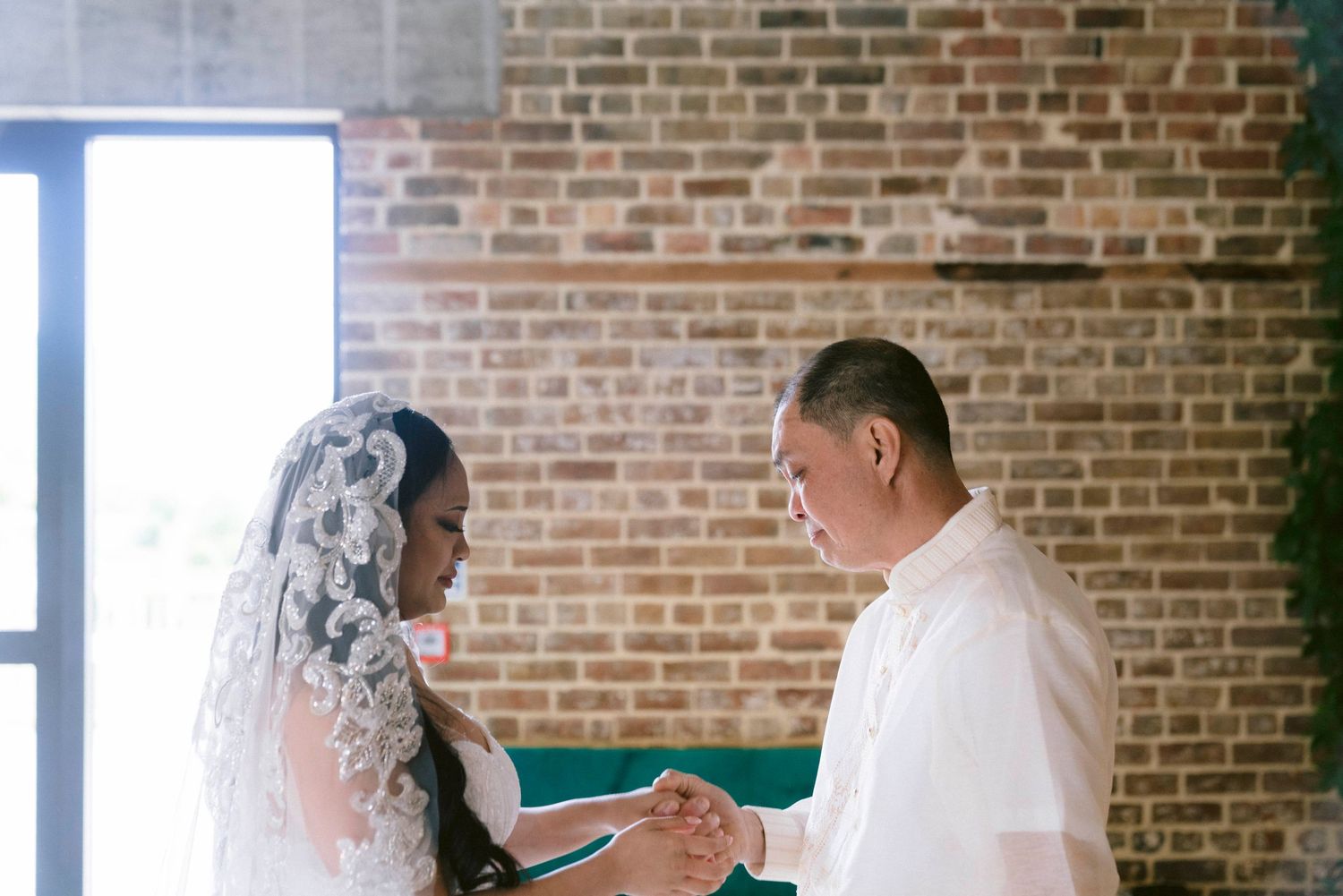 Elegant wedding ceremony setup in rustic brick-walled venue with natural light streaming through windows.