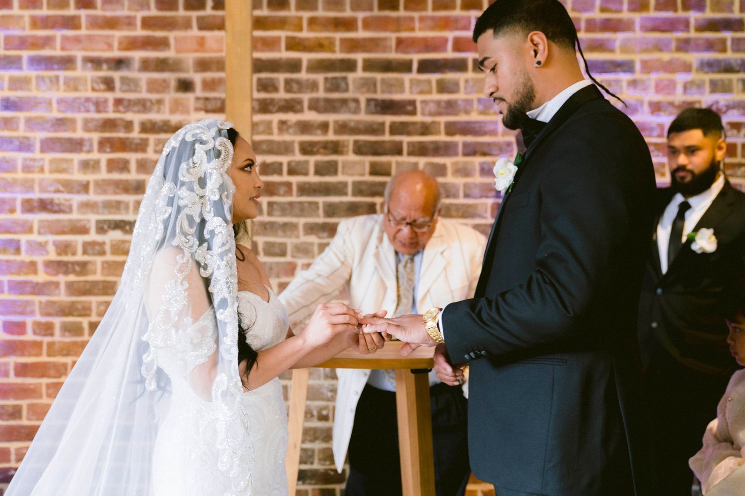 Reception guests seated at tables in an elegant brick-walled venue during wedding festivities.
