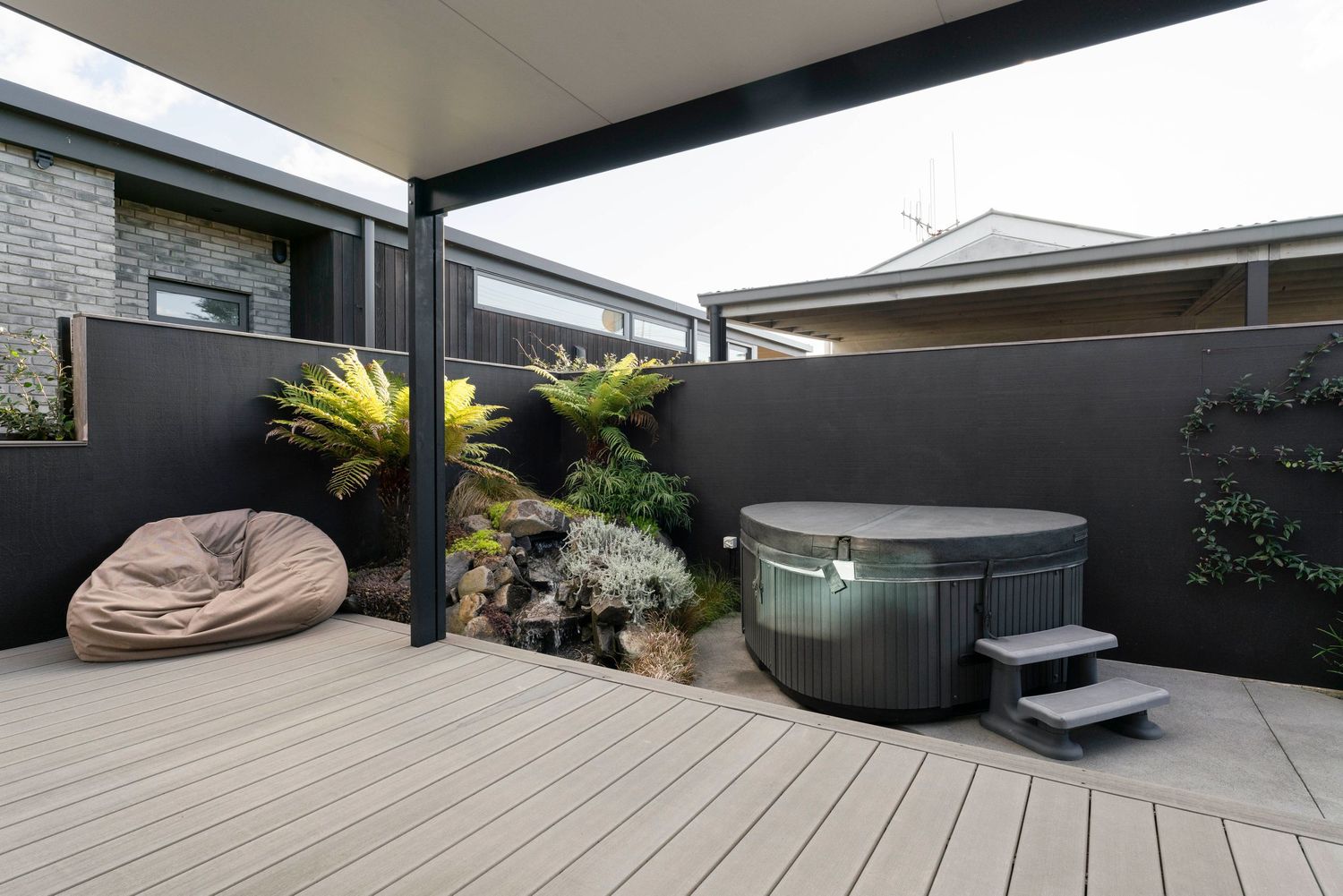 Private outdoor deck space featuring a hot tub and comfortable lounge seating under a covered pergola.