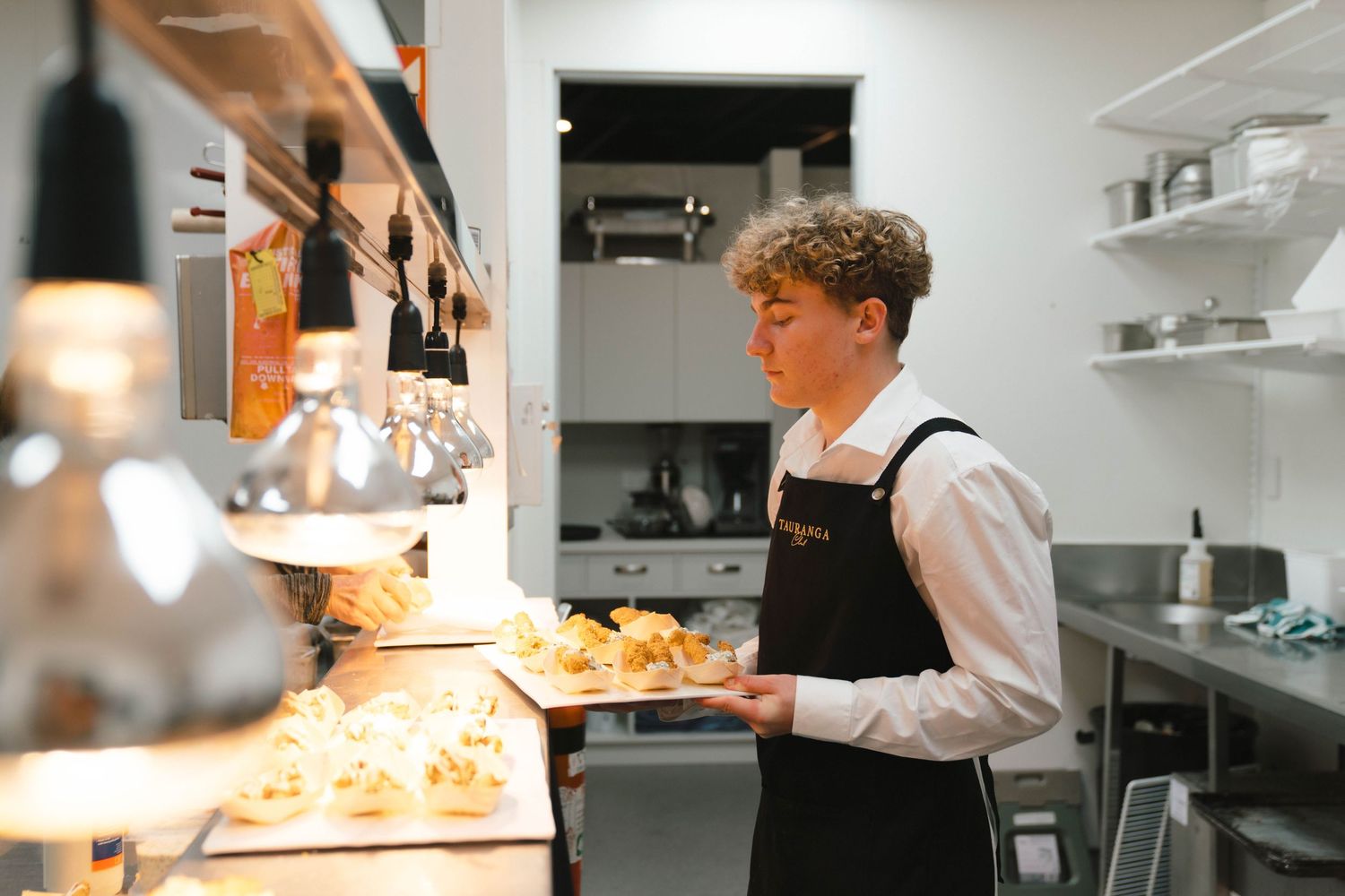 Staff member in apron preparing food at an illuminated service counter.