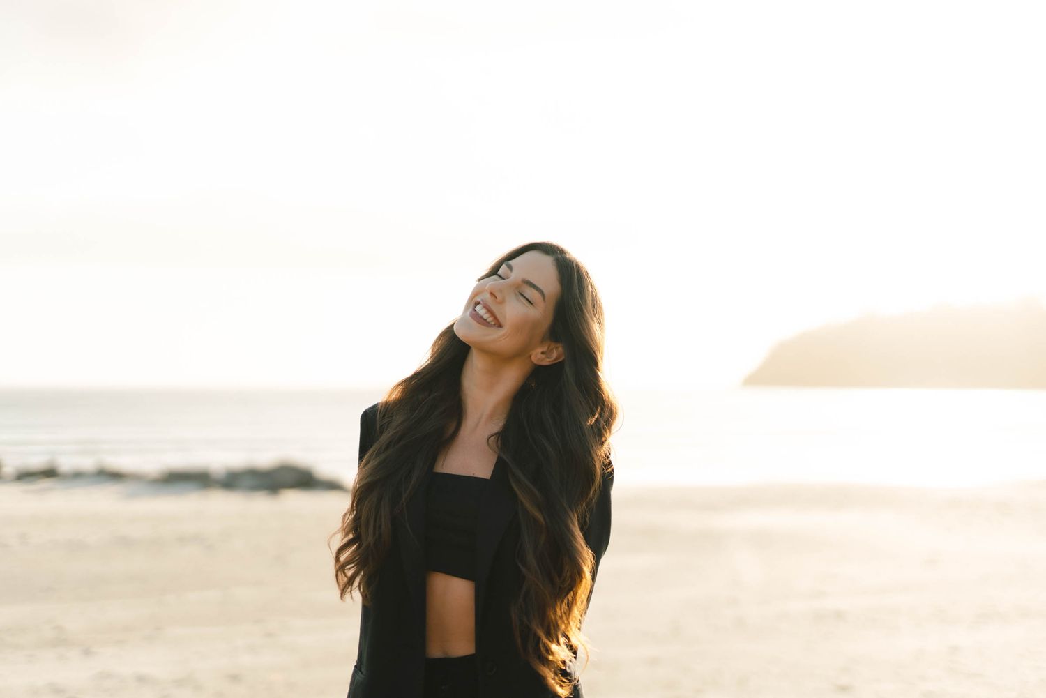 A sunset photoshoot shows a figure in black lying in tall golden grass.