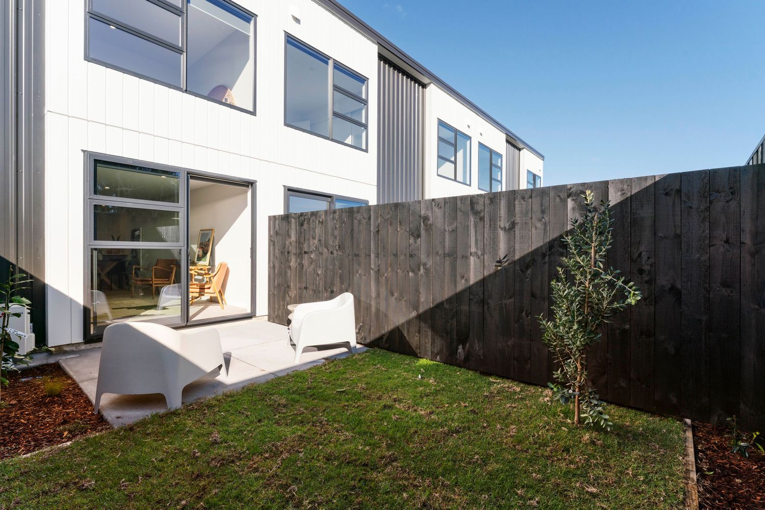Contemporary white residential buildings with grassy landscaping and minimalist outdoor spaces.